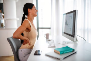 woman with waist ache while sitting at workplace at home