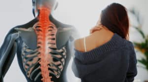 Close up of a brunette woman massaging her neck in a bedroom