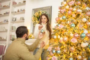 happy couple putting christmas bals on a christmas tree