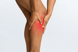 Black woman has leg pain, grabbing her ache for relief
