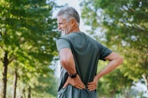 Man holding his back in pain, needing herniated disc surgery in New York, NY